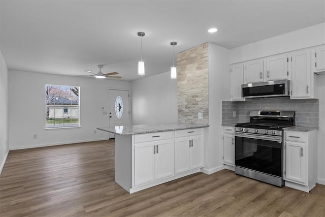 kitchen with white cabinets, stainless steel appliances, a ceiling fan, a peninsula, and tasteful backsplash