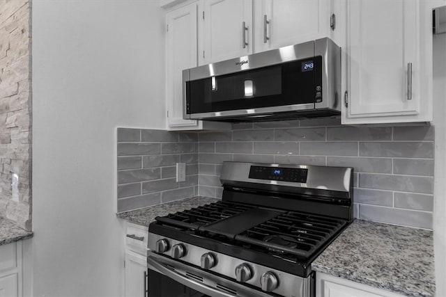 kitchen featuring light stone counters, backsplash, white cabinetry, and stainless steel appliances