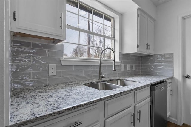 kitchen featuring white cabinets, stainless steel dishwasher, tasteful backsplash, and a sink