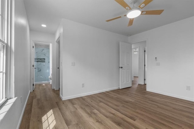 unfurnished bedroom with baseboards, wood finished floors, ceiling fan, and multiple windows