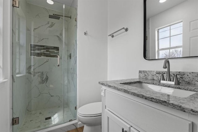 full bath featuring toilet, vanity, and a marble finish shower