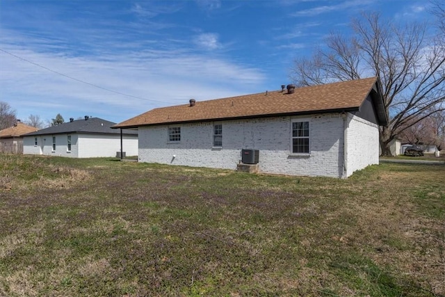 rear view of property featuring central AC, brick siding, and a yard