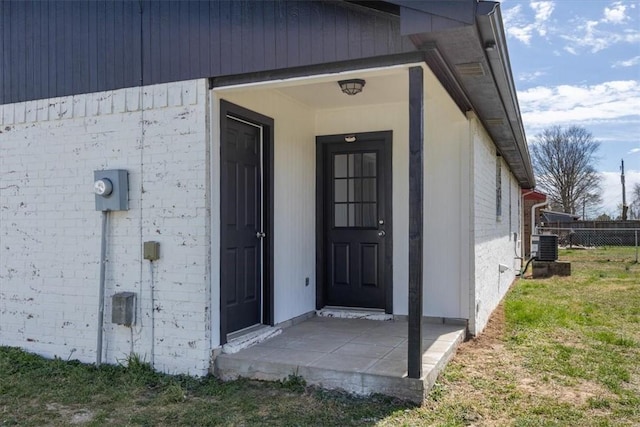 view of exterior entry with central air condition unit and fence