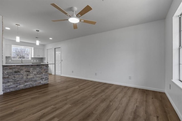 unfurnished living room featuring dark wood-type flooring, a ceiling fan, baseboards, and recessed lighting