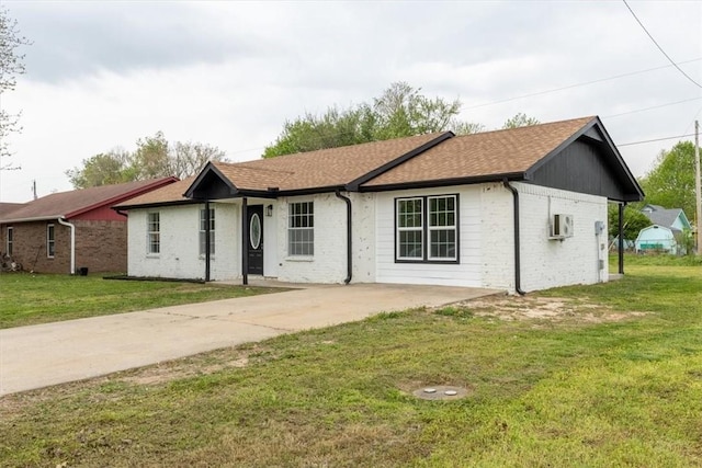 ranch-style home with brick siding, a shingled roof, a front yard, and concrete driveway