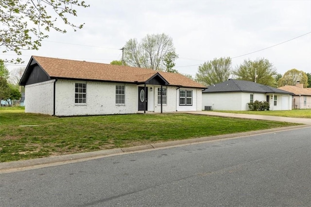 ranch-style house featuring driveway, a front lawn, brick siding, and central AC