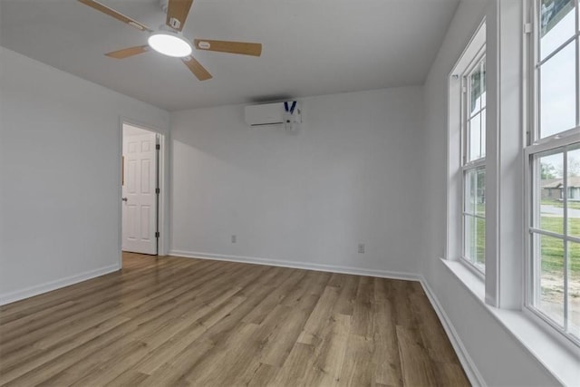 empty room featuring baseboards, a ceiling fan, wood finished floors, and a wall mounted AC