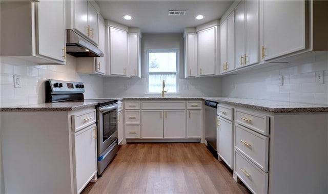 402 NE 4th Ave, Gravette, AR 72736 - kitchen with appliances with stainless steel finishes, under cabinet range hood, a sink, wood finished floors, and white cabinetry