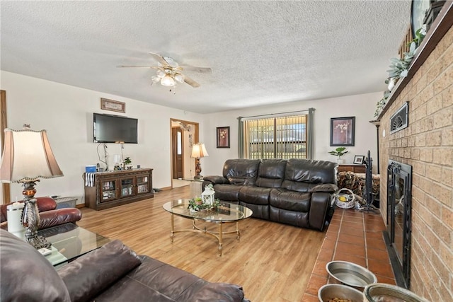 22965 Davis Valley Rd, Gentry, AR 72734 - living area with a brick fireplace, a textured ceiling, wood finished floors, and a ceiling fan