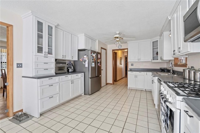 22965 Davis Valley Rd, Gentry, AR 72734 - kitchen with white cabinetry, glass insert cabinets, stainless steel appliances, dark countertops, and ceiling fan
