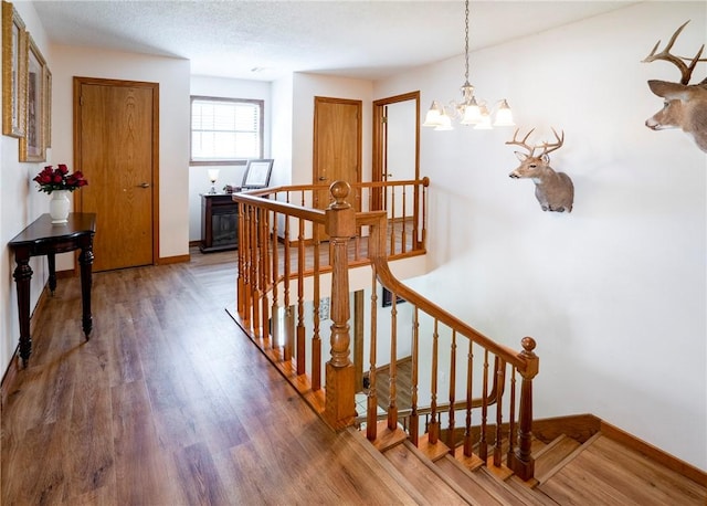 22965 Davis Valley Rd, Gentry, AR 72734 - stairway featuring an inviting chandelier, a textured ceiling, baseboards, and wood finished floors
