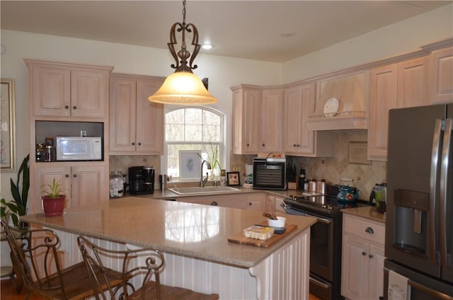 kitchen with a peninsula, a kitchen bar, stainless steel appliances, a sink, and backsplash