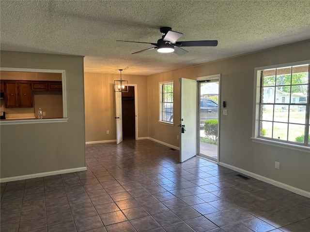 empty room with a chandelier, ceiling fan, baseboards, and a textured ceiling