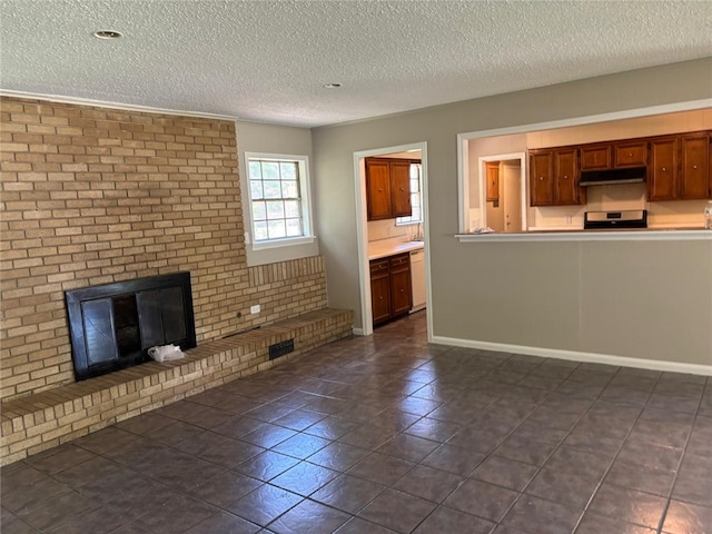 unfurnished living room featuring a textured ceiling, a fireplace, baseboards, and dark tile patterned floors