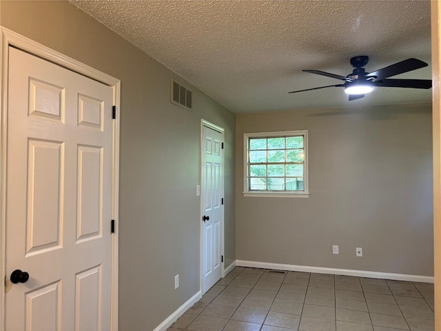 tiled spare room with a textured ceiling, baseboards, and ceiling fan