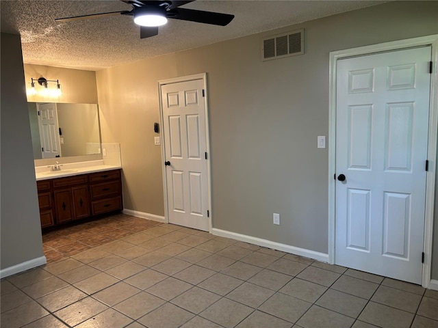 bathroom with a ceiling fan, tile patterned floors, a textured ceiling, vanity, and baseboards