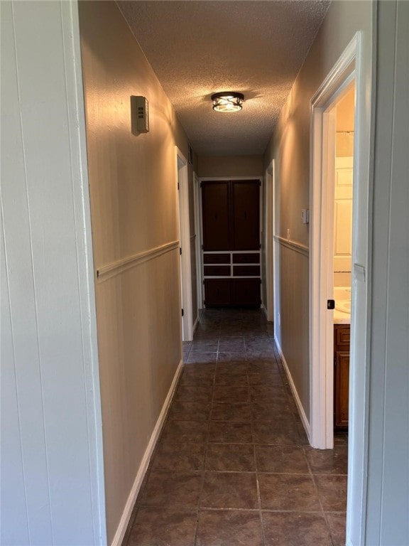hallway with a textured ceiling and baseboards