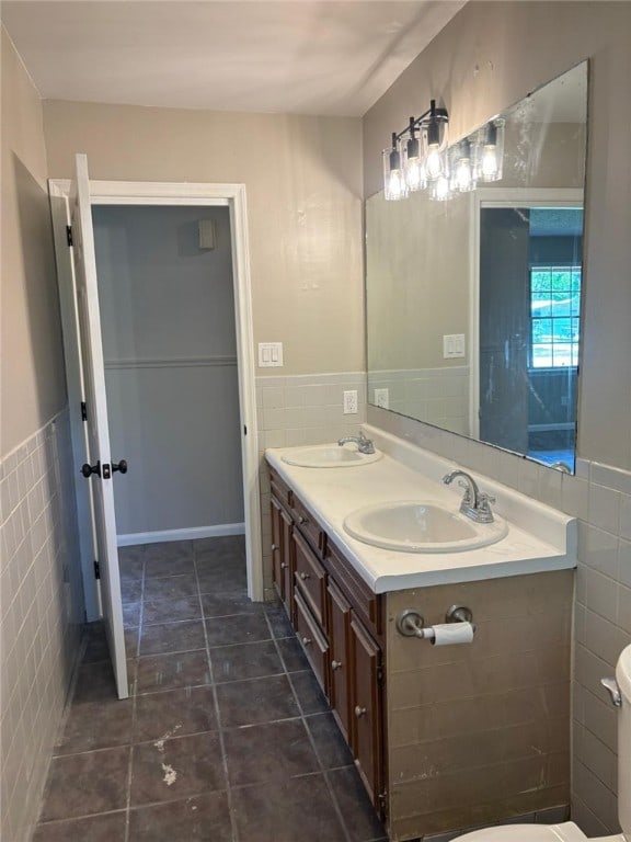 full bath featuring tile walls, wainscoting, toilet, double vanity, and tile patterned flooring