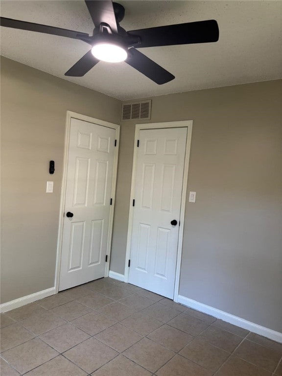 unfurnished bedroom featuring light tile patterned floors, baseboards, and a ceiling fan