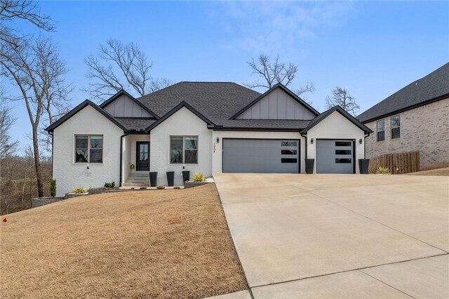1904 NE Frost Dr, Bentonville, AR 72712 - modern farmhouse style home with driveway, roof with shingles, fence, board and batten siding, and a garage