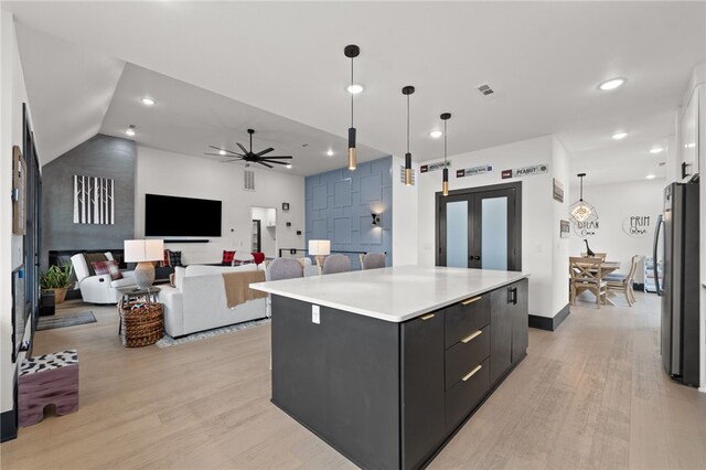 1904 NE Frost Dr, Bentonville, AR 72712 - kitchen featuring light countertops, a center island, light wood-style floors, freestanding refrigerator, and dark cabinets