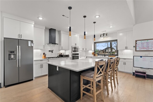 1904 NE Frost Dr, Bentonville, AR 72712 - kitchen with wall chimney range hood, white cabinetry, light wood-style flooring, and stainless steel appliances