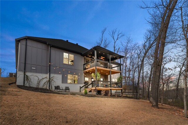 1904 NE Frost Dr, Bentonville, AR 72712 - back of property at dusk with a ceiling fan, a balcony, stairway, and central AC unit