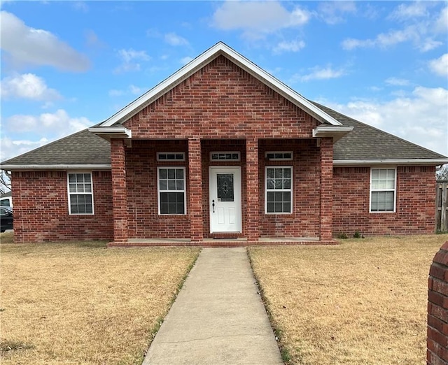 view of front of home with brick siding, roof with shingles, and a front lawn