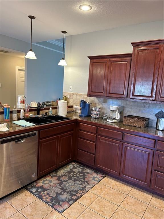 kitchen with a sink, stainless steel dishwasher, hanging light fixtures, light tile patterned floors, and dark countertops