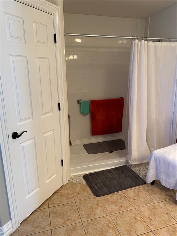 bathroom with a shower with shower curtain and tile patterned flooring