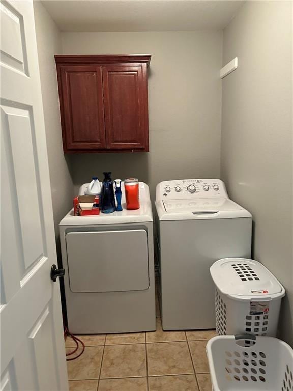 laundry area with washing machine and clothes dryer, cabinet space, and light tile patterned floors