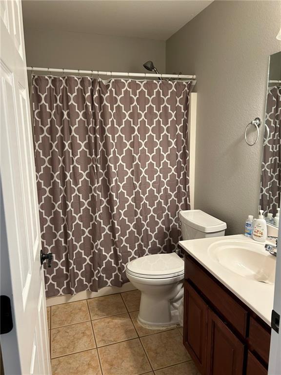 bathroom with curtained shower, toilet, tile patterned floors, and vanity
