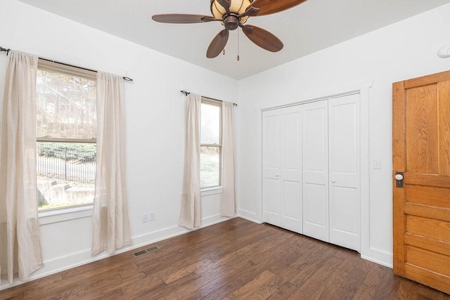 unfurnished bedroom with a ceiling fan, visible vents, baseboards, a closet, and dark wood-style floors