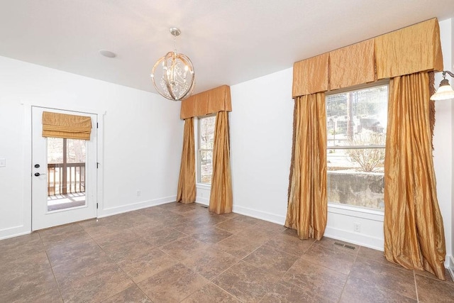 unfurnished room with baseboards, a notable chandelier, a wealth of natural light, and visible vents