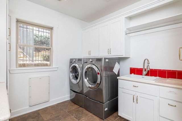 clothes washing area with a sink, baseboards, cabinet space, and washer and clothes dryer