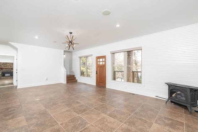 unfurnished living room with a wood stove, stairway, baseboards, a notable chandelier, and recessed lighting