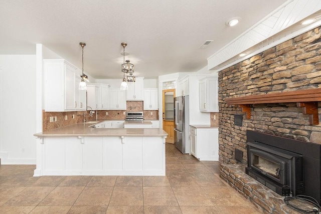 kitchen featuring a peninsula, light countertops, a sink, appliances with stainless steel finishes, and backsplash