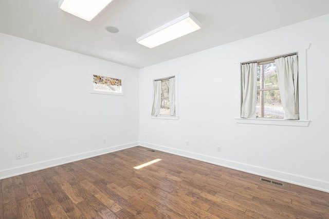 empty room featuring baseboards, wood finished floors, and visible vents