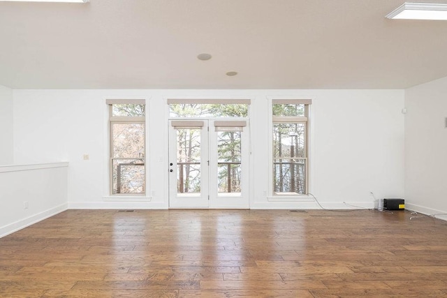 unfurnished room featuring plenty of natural light, wood-type flooring, baseboards, and visible vents