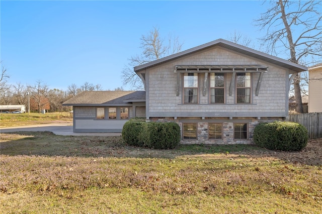 view of front of home featuring fence, a front lawn, and stone siding