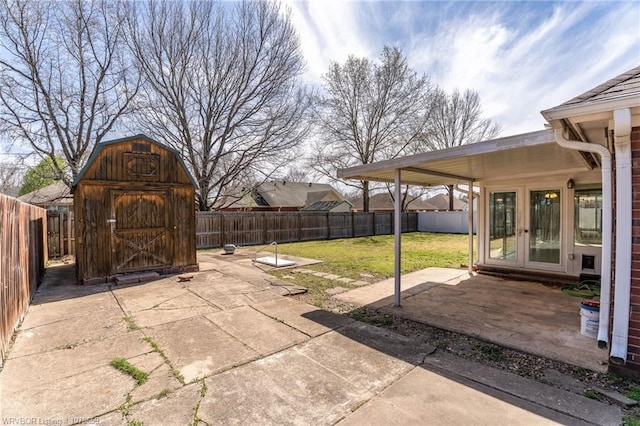 view of patio / terrace featuring a fenced backyard, an outbuilding, a shed, and french doors
