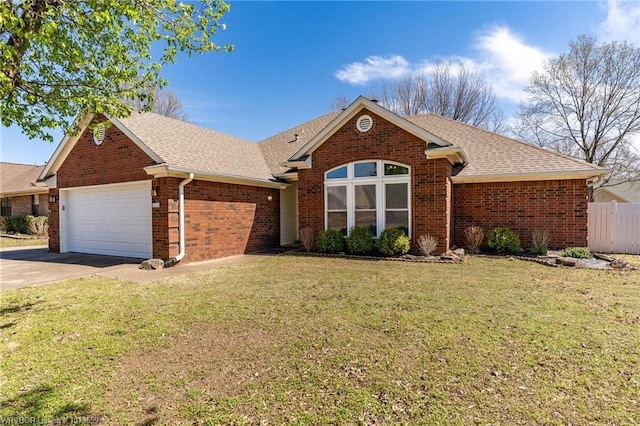 ranch-style home with roof with shingles, an attached garage, driveway, brick siding, and a front yard