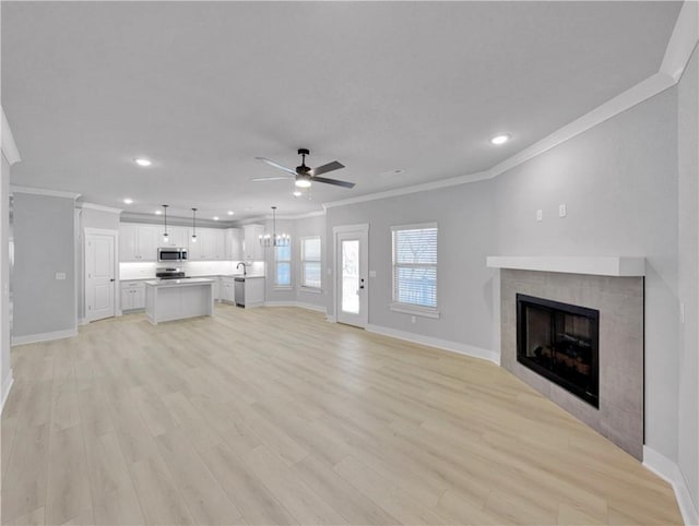 6 Osborne Ln, Bella Vista, AR 72715 - unfurnished living room featuring crown molding, baseboards, ceiling fan, a tiled fireplace, and light wood finished floors