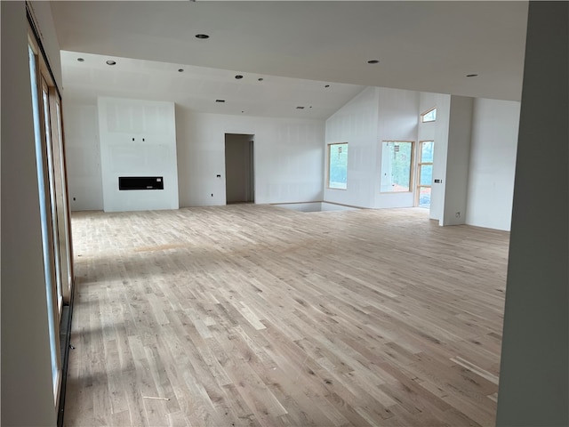 unfurnished living room with vaulted ceiling and light wood-style flooring
