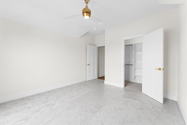 unfurnished bedroom with a spacious closet, baseboards, a ceiling fan, and carpet