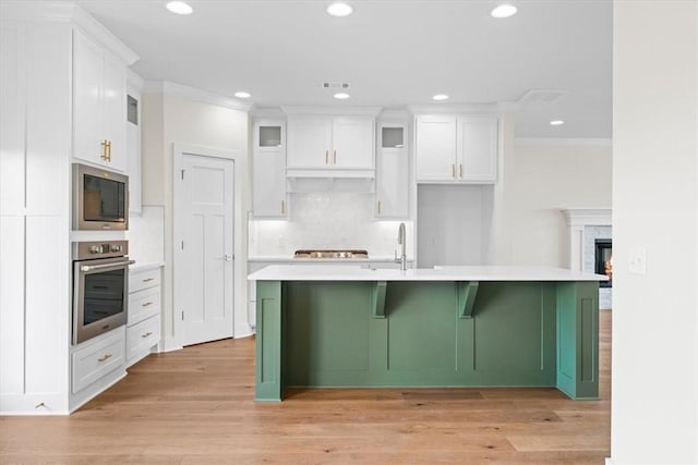 kitchen featuring light wood-type flooring, light countertops, white cabinetry, and appliances with stainless steel finishes