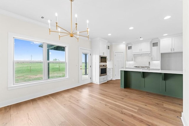 kitchen with stainless steel appliances, light countertops, white cabinetry, light wood-type flooring, and a notable chandelier