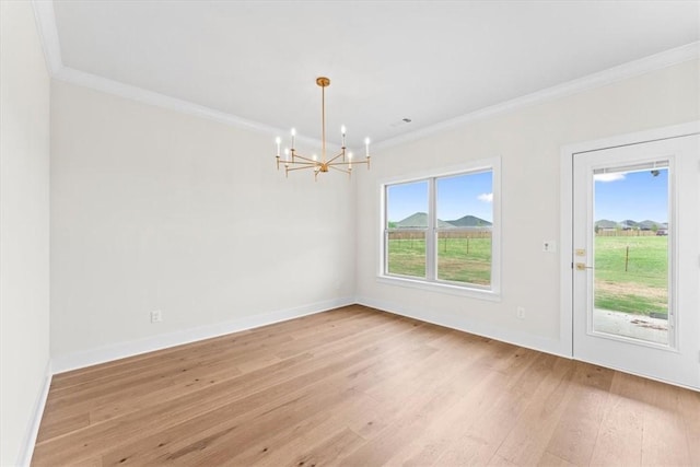 unfurnished dining area featuring light wood-style flooring, baseboards, a notable chandelier, and crown molding
