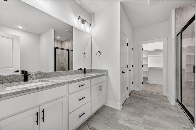 98 N Banner Ave, Farmington, AR 72730 - bathroom featuring a stall shower, double vanity, a spacious closet, baseboards, and marble look tiles