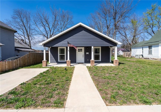 bungalow-style home with a front lawn, covered porch, and fence